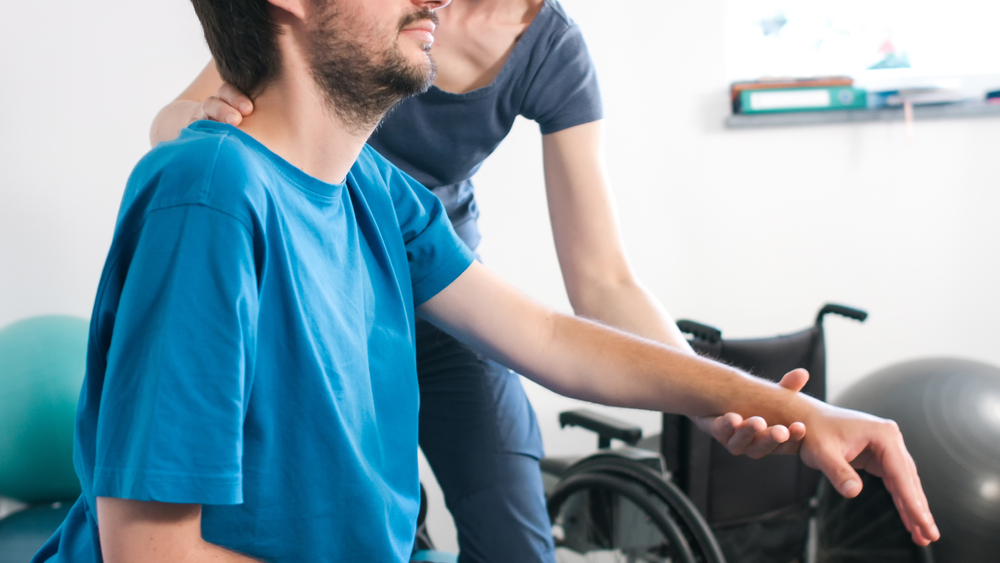 woman helping man in a wheel chair in his Supported Independent Living home